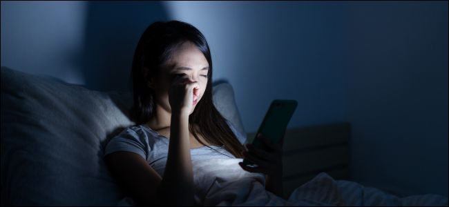 Kvinner med øye belastning ved hjelp av en lys mobiltelefon i sengen